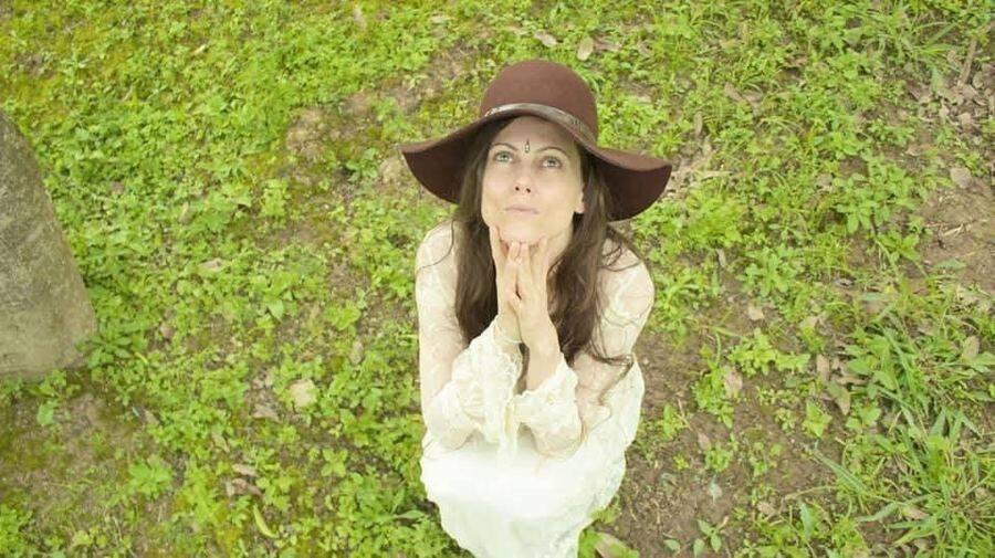 Michela in prayer, hat and hands folded, in the field — Prayers & Invocation