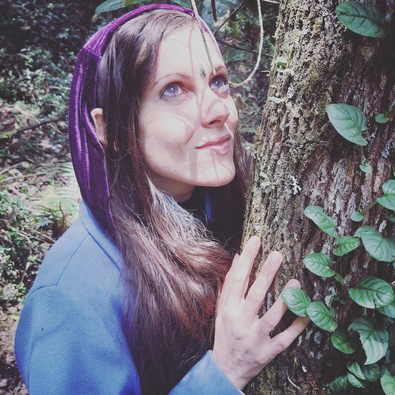 Michela de cerca, tocando la corteza de un árbol, con luz moteada en su rostro