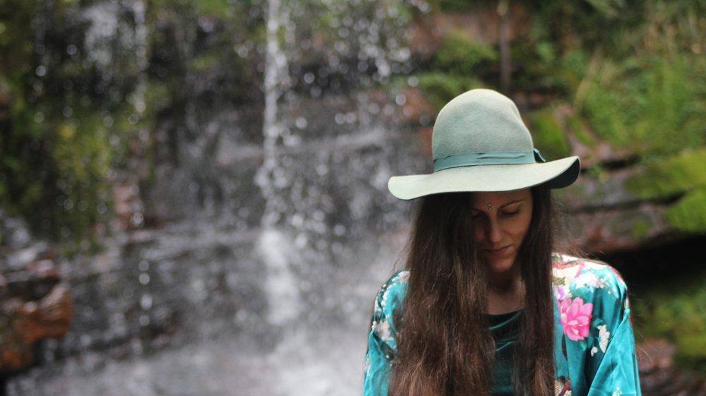 Michela at a waterfall, wearing a wide-brim hat